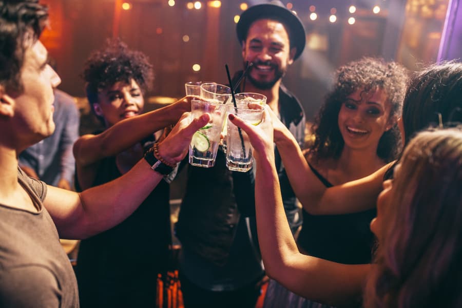 a group of friends toasting cocktails at a bar